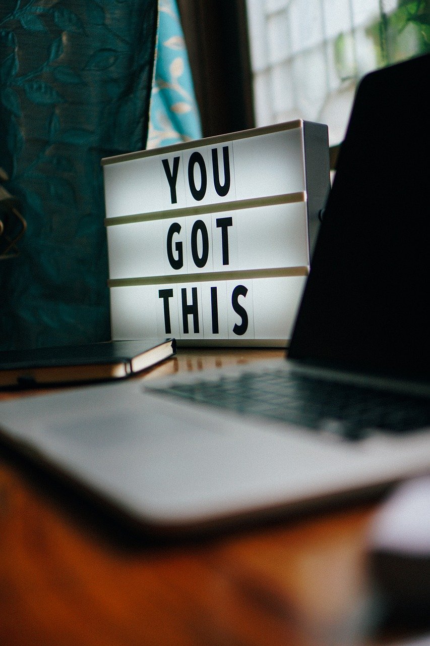 A motivational lightbox sign reading "YOU GOT THIS" on a desk next to a laptop.
